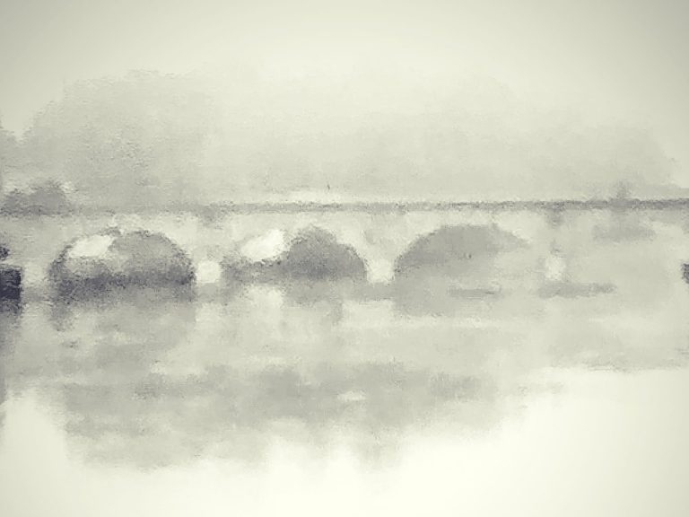 Puente sobre un río en un entorno brumoso y difuso.